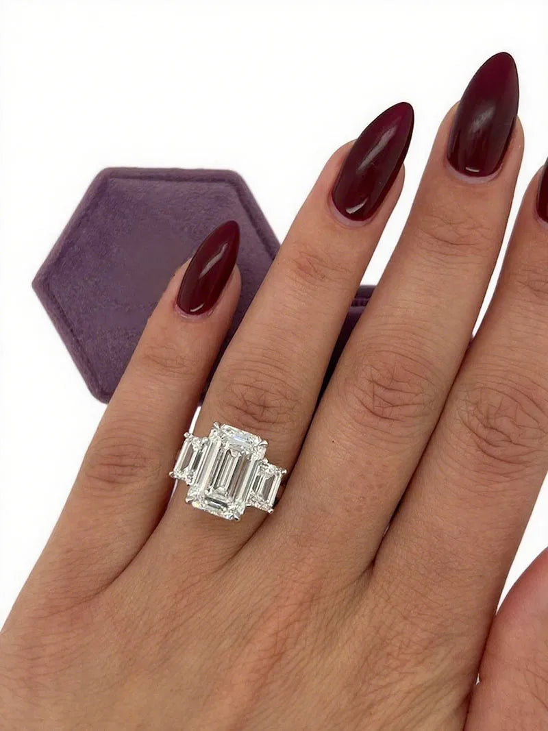 Gold three-stone ring with emerald-cut diamond